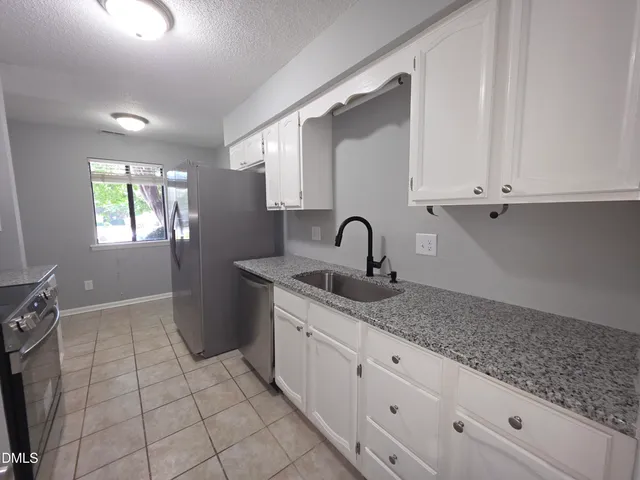 a kitchen with granite countertop white cabinets and window