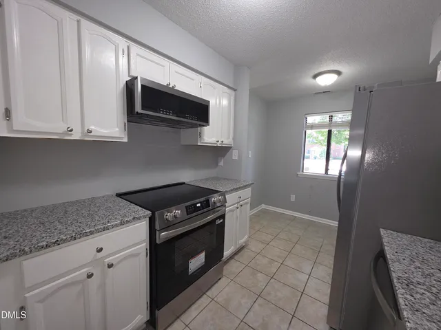 a kitchen with granite countertop a stove a sink and a microwave