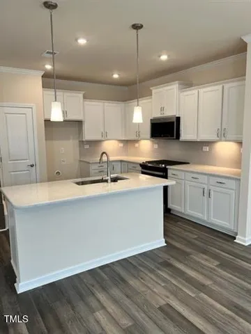 a kitchen with stainless steel appliances granite countertop a sink a stove a refrigerator and white cabinets