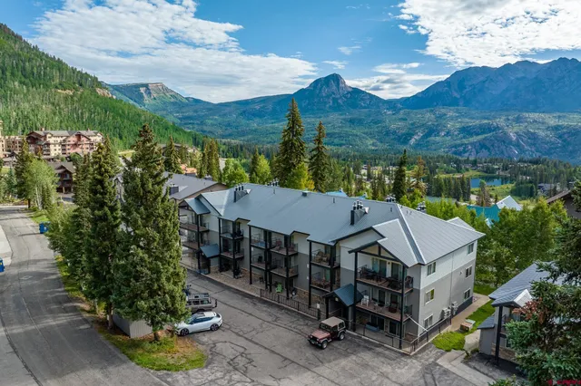 an aerial view of a house with a yard and mountain view in back