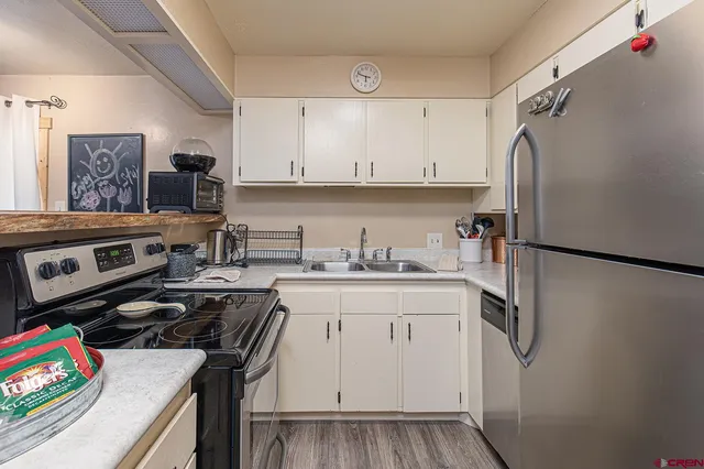 a kitchen with stainless steel appliances a stove a refrigerator and a sink with wooden floor