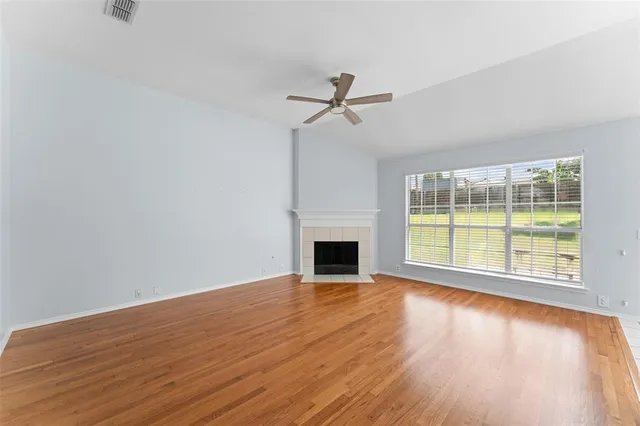 a view of empty room with wooden floor and fireplace