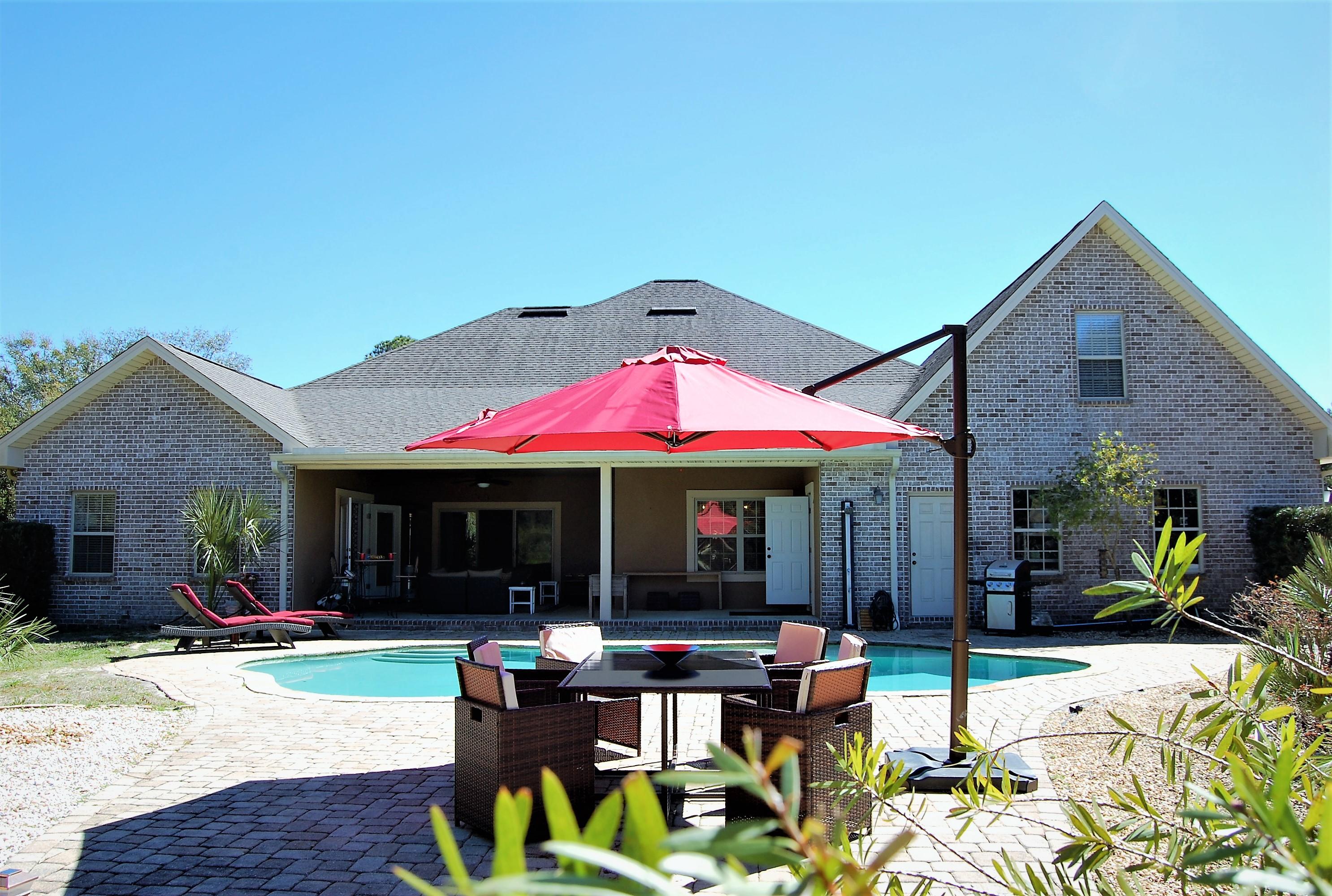 2497 Crescent Road Navarre, FL 32566 - Photo 46 of 51 a patio with a table and chairs under an umbrella