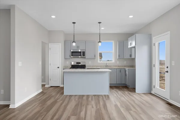 a kitchen with stainless steel appliances granite countertop a refrigerator a sink dishwasher a stove and white cabinets with wooden floor