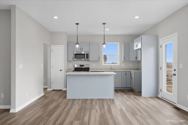 a kitchen with stainless steel appliances granite countertop a refrigerator a sink dishwasher a stove and white cabinets with wooden floor