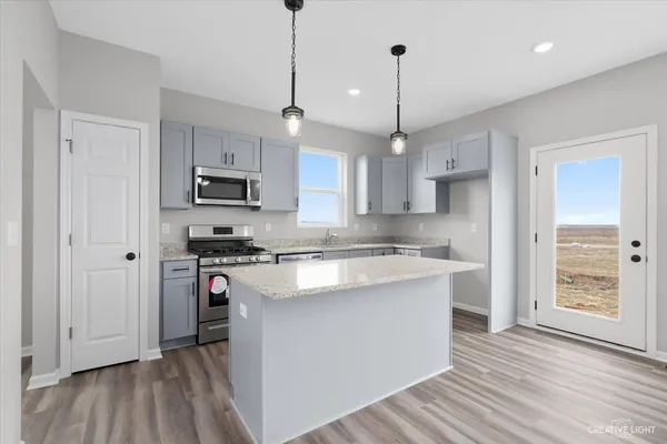 a kitchen with stainless steel appliances granite countertop a sink a stove a refrigerator and white cabinets with wooden floor