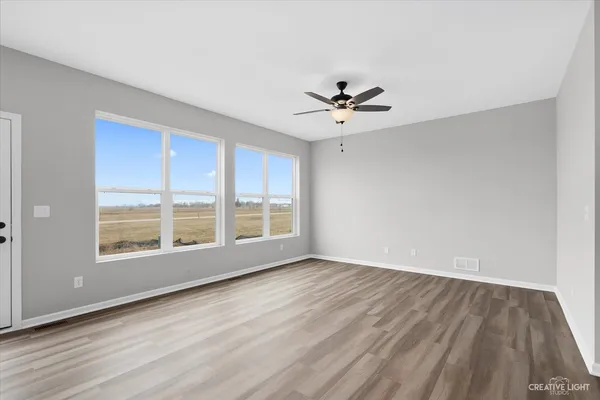 a view of wooden floor and a chandelier fan in a room