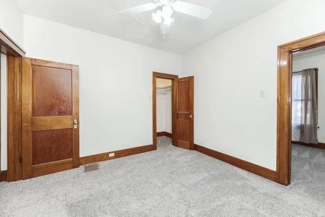 an empty room with closet and a chandelier fan