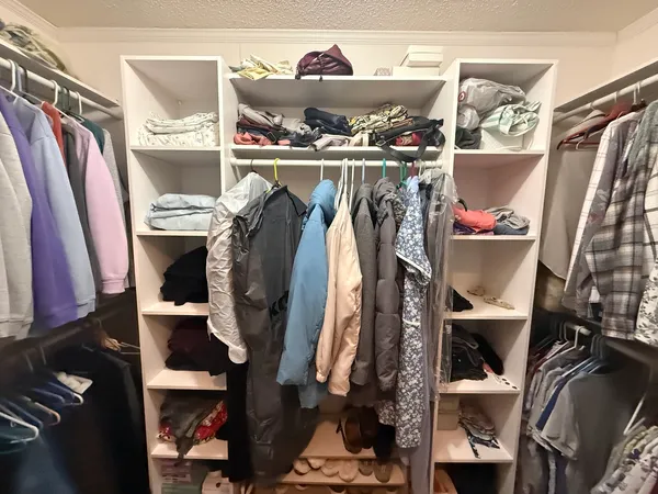 a view of walk in closet with clothes and shoes