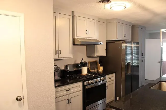 a kitchen with stainless steel appliances granite countertop a refrigerator and a stove