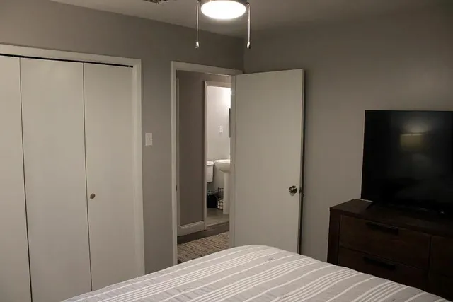 a bedroom with a bed and a flat tv screen on the dresser