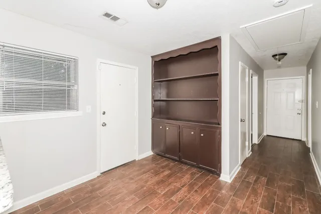 a view of an empty room with wooden floor and a window
