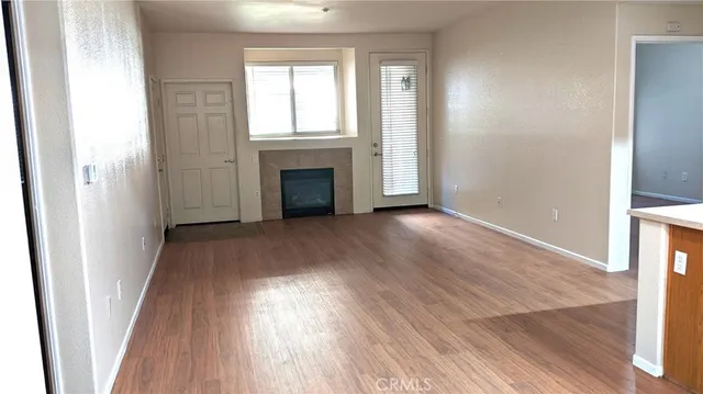 an empty room with wooden floor fireplace and windows