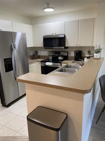 a kitchen with stainless steel appliances a refrigerator a stove a sink a microwave a refrigerator and white cabinets