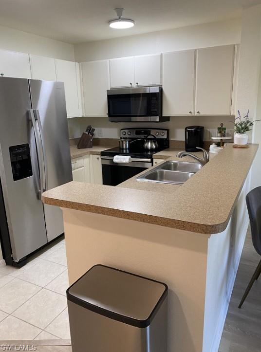 4430 Botanical Pl Circle, Unit 303 Naples, FL 34112 - Photo 12 of 22 a kitchen with stainless steel appliances a refrigerator a stove a sink a microwave a refrigerator and white cabinets