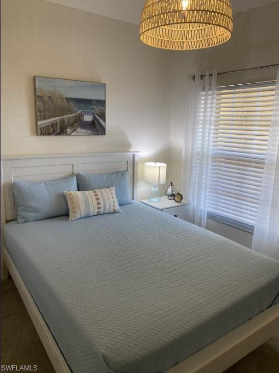 4430 Botanical Pl Circle, Unit 303 Naples, FL 34112 - Photo 9 of 22 a bed sitting in a bedroom next to a window
