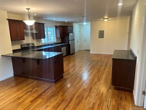 a kitchen with kitchen island granite countertop wooden floors and a sink