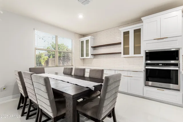 a kitchen with a dining table chairs and white cabinets