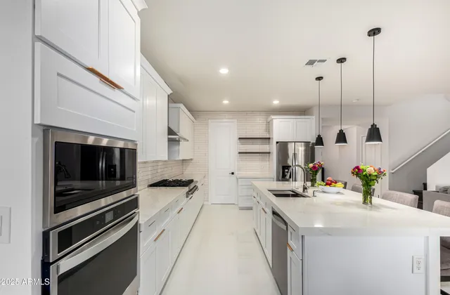 a kitchen with stainless steel appliances kitchen island granite countertop a sink a stove and a wooden floors