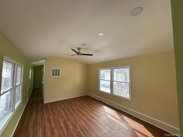a view of empty room with wooden floor and fan