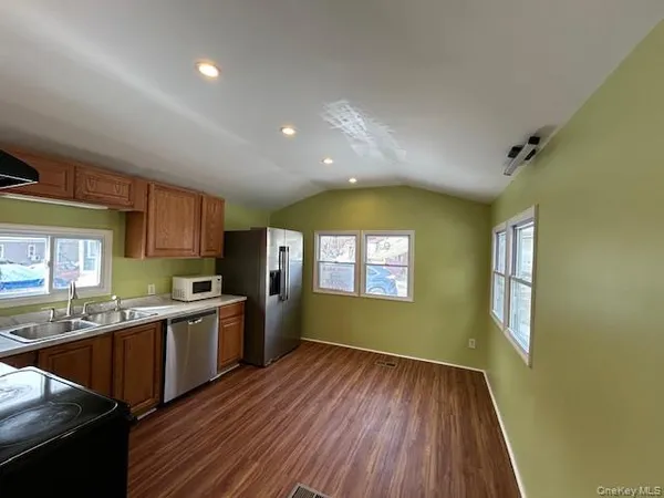 a large kitchen with stainless steel appliances granite countertop a stove a sink dishwasher and a large window with wooden floor