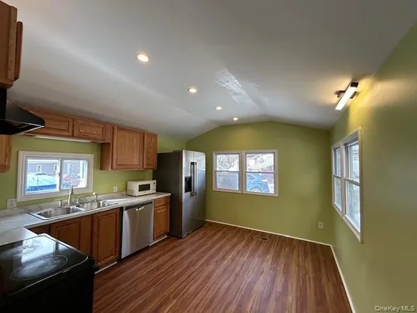 a kitchen with stainless steel appliances granite countertop a sink dishwasher a stove and a refrigerator with wooden floor