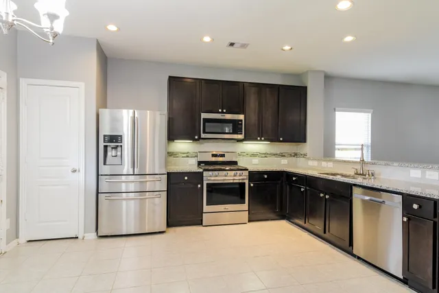 a kitchen with stainless steel appliances granite countertop a stove a refrigerator and a sink with wooden cabinets