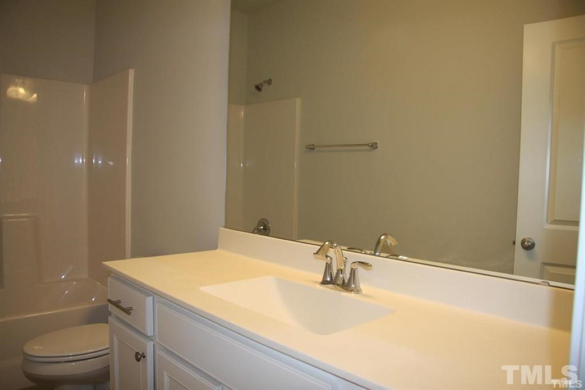 2919 Sunflower Road Apex, NC 27502 - Photo 28 of 34 a bathroom with a granite countertop sink a toilet and a mirror