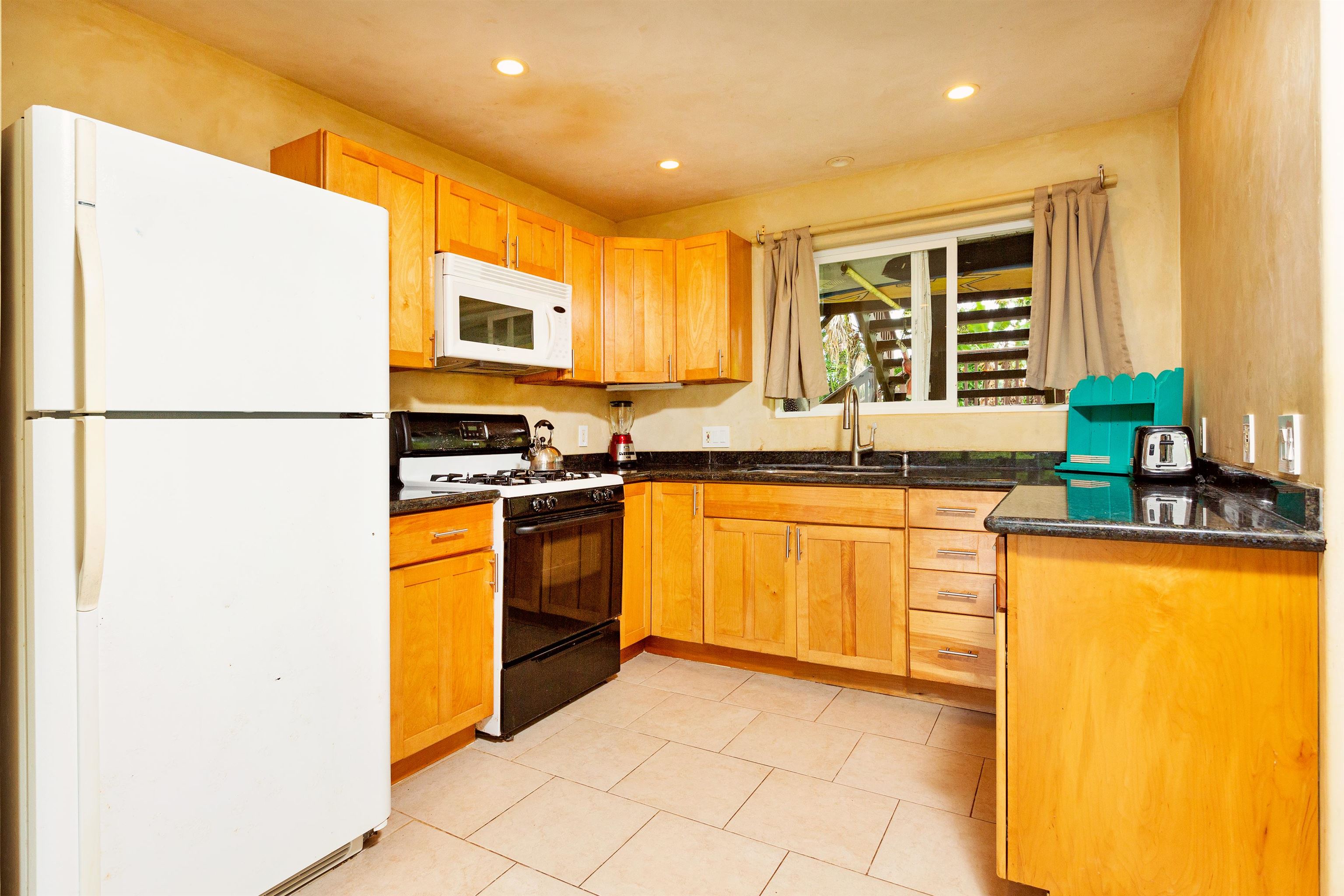 4509 Opana Place Haiku, HI 96708 - Photo 18 of 26 a kitchen with stainless steel appliances granite countertop a stove a sink and a refrigerator