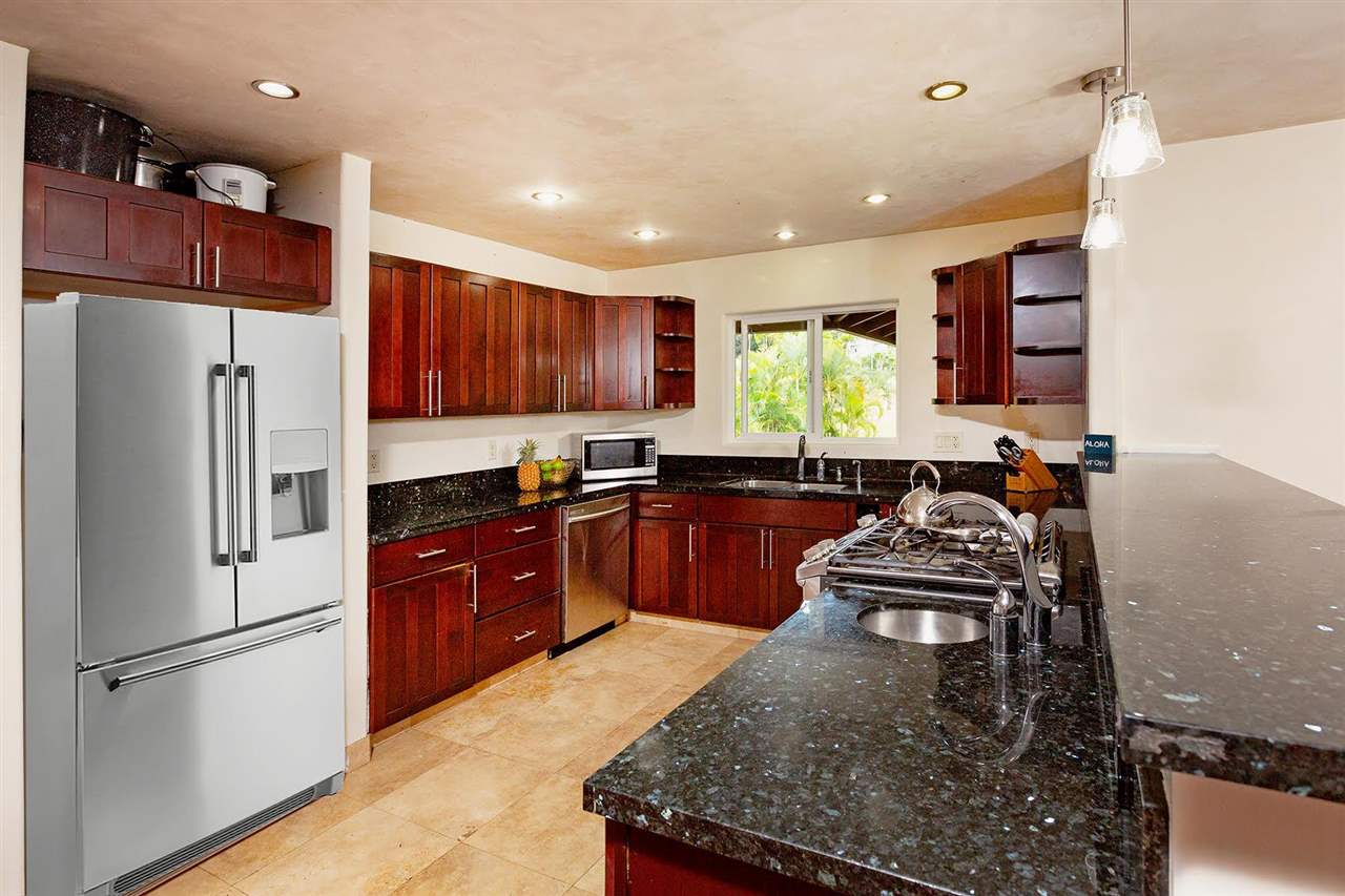 4509 Opana Place Haiku, HI 96708 - Photo 9 of 26 a kitchen with stainless steel appliances granite countertop a refrigerator sink and wooden cabinets