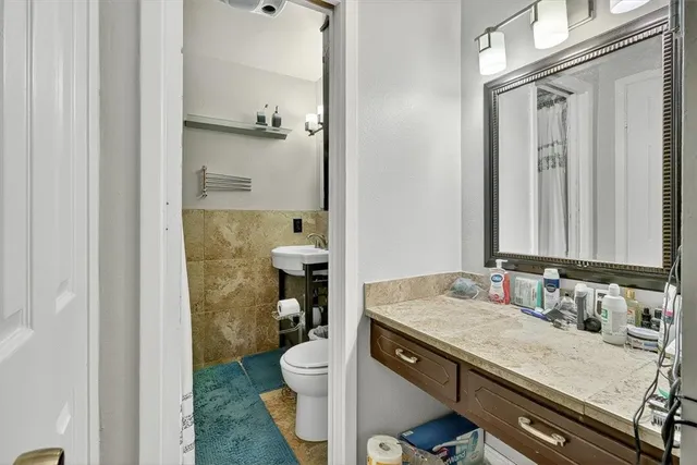 a bathroom with a granite countertop sink a toilet and a shower