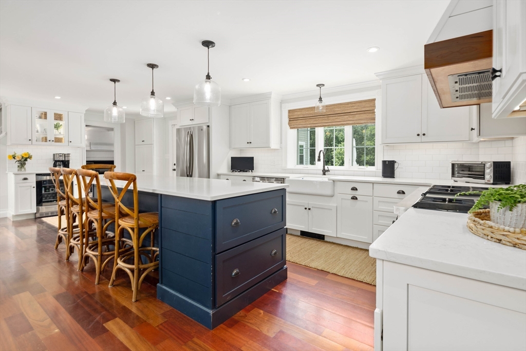 17 Common Street Scituate, MA 02066 - Photo 3 of 39 a large white kitchen with stainless steel appliances kitchen island granite countertop a stove a sink dishwasher and white cabinets with wooden floor