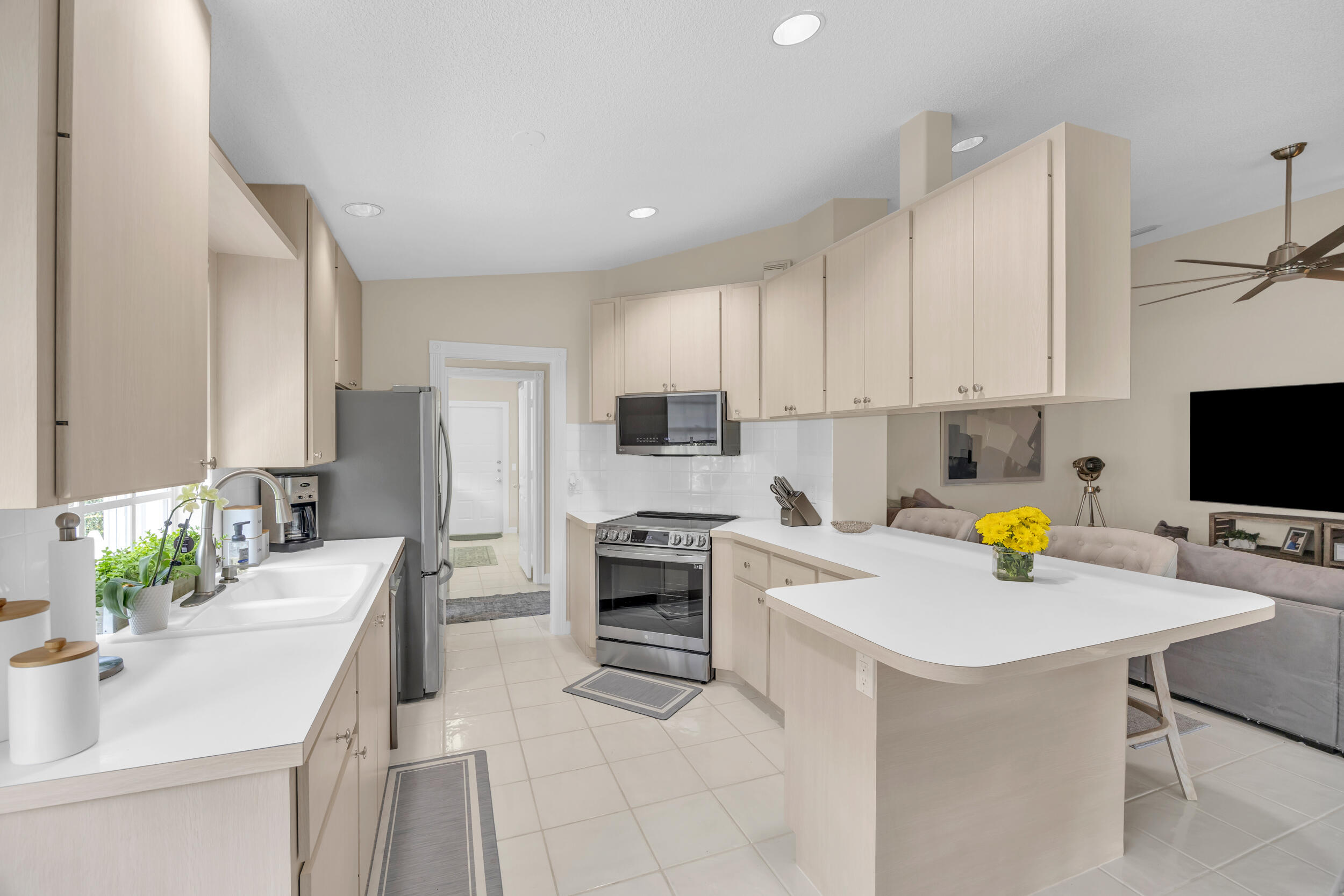 233 Brier Circle Jupiter, FL 33458 - Photo 5 of 31 a kitchen with a sink stainless steel appliances and white cabinets