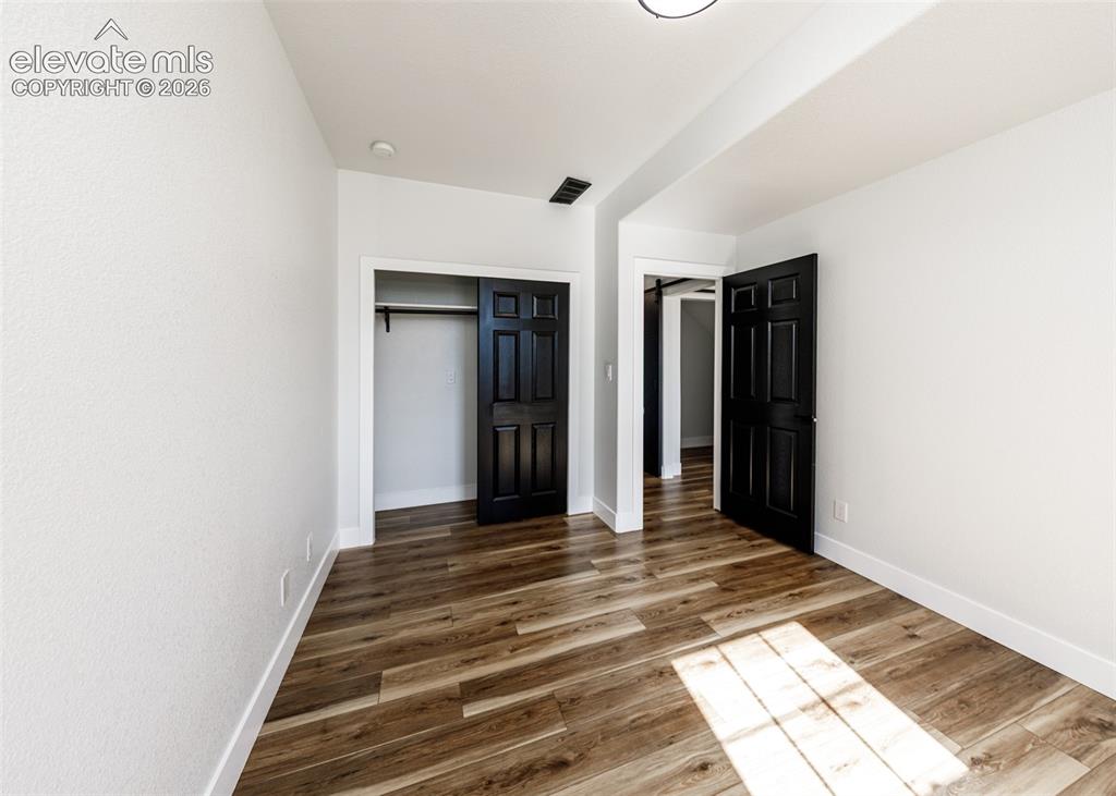 1120 Newton Road Pueblo, CO 81005 - Photo 32 of 46 a view of a hallway with wooden floor and a bathroom
