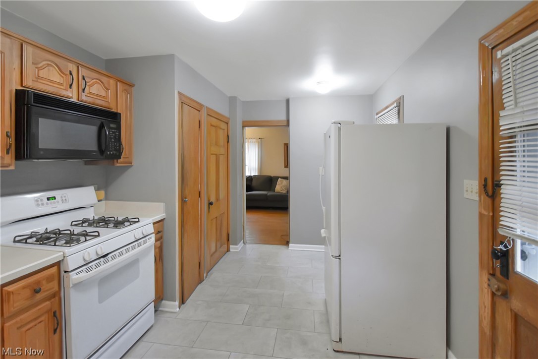 1068 Rushleigh Road Cleveland Heights, OH 44121 - Photo 8 of 22 Kitchen with white appliances and light tile floors