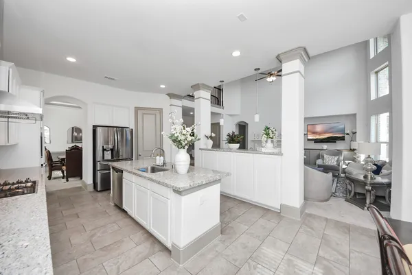 a large white kitchen with a refrigerator a stove a sink and a dining table with wooden floor