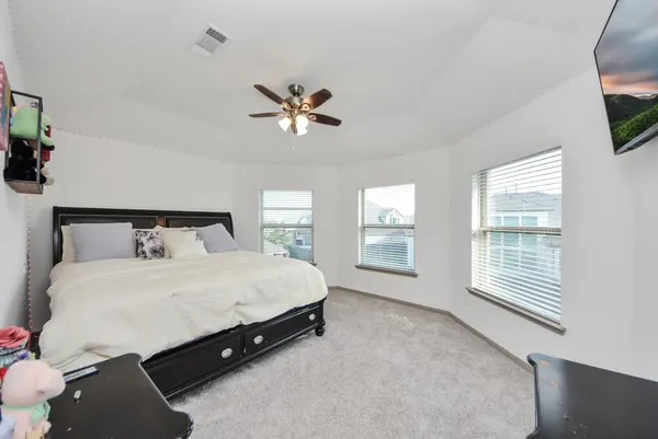 a spacious bedroom with a bed a flat screen tv and a large window with the outer view