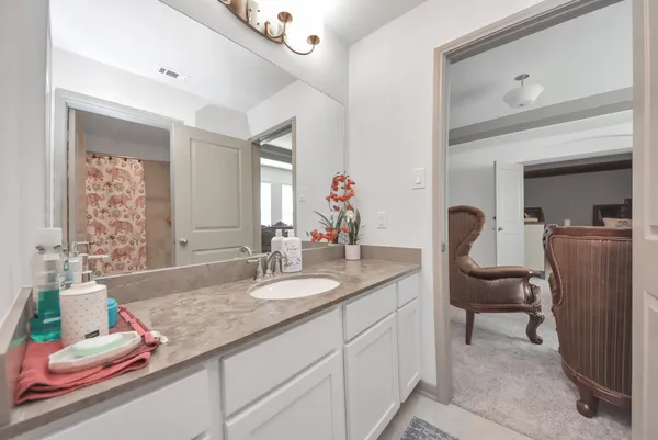 a en suite bathroom with a granite countertop sink and a mirror