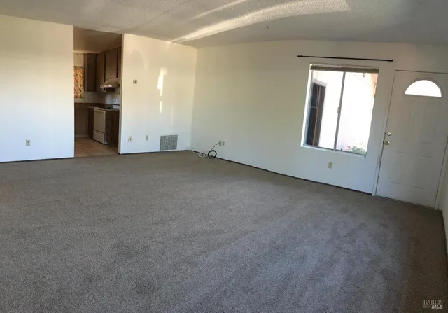 an empty room with a window and a kitchen