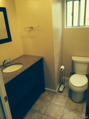 a bathroom with a granite countertop sink and a toilet