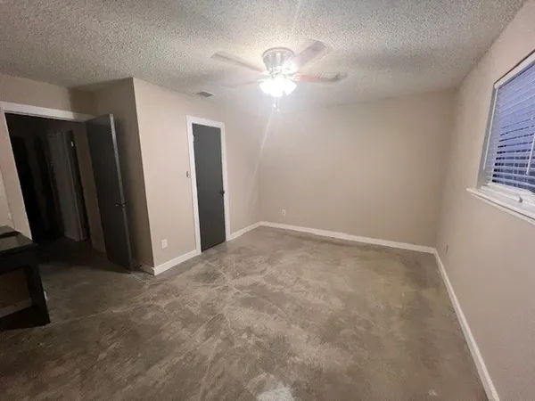 an empty room with windows and fan