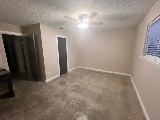 an empty room with windows and fan