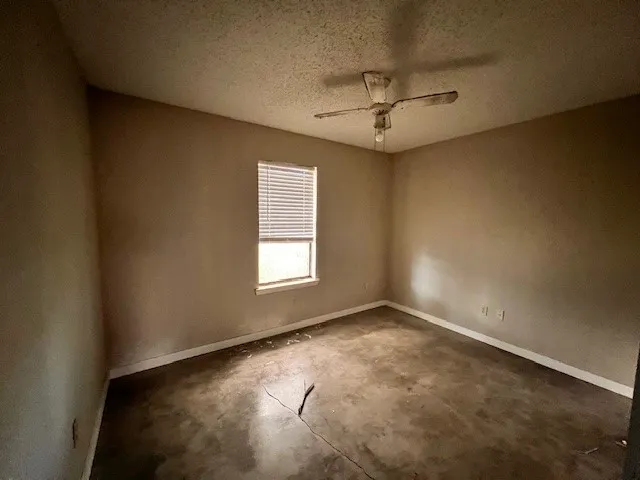 an empty room with windows and fan