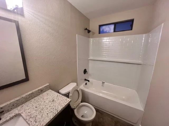 a bathroom with a granite countertop sink toilet and a bathtub