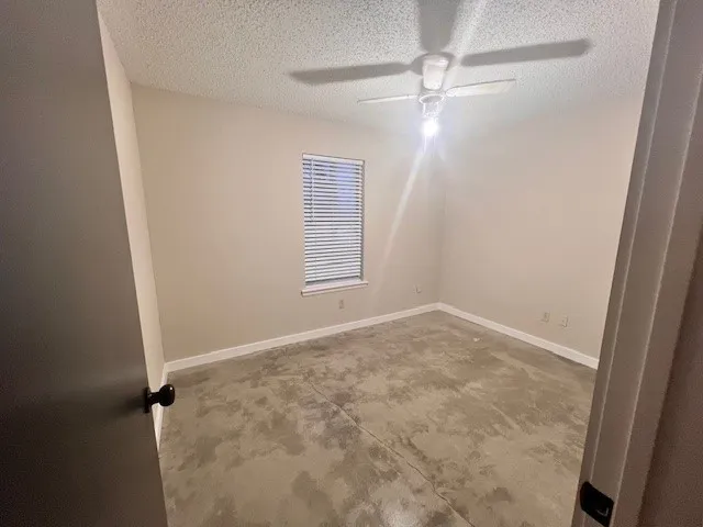 an empty room with windows and fan