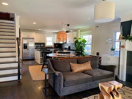 a living room with stainless steel appliances furniture a rug and a kitchen view