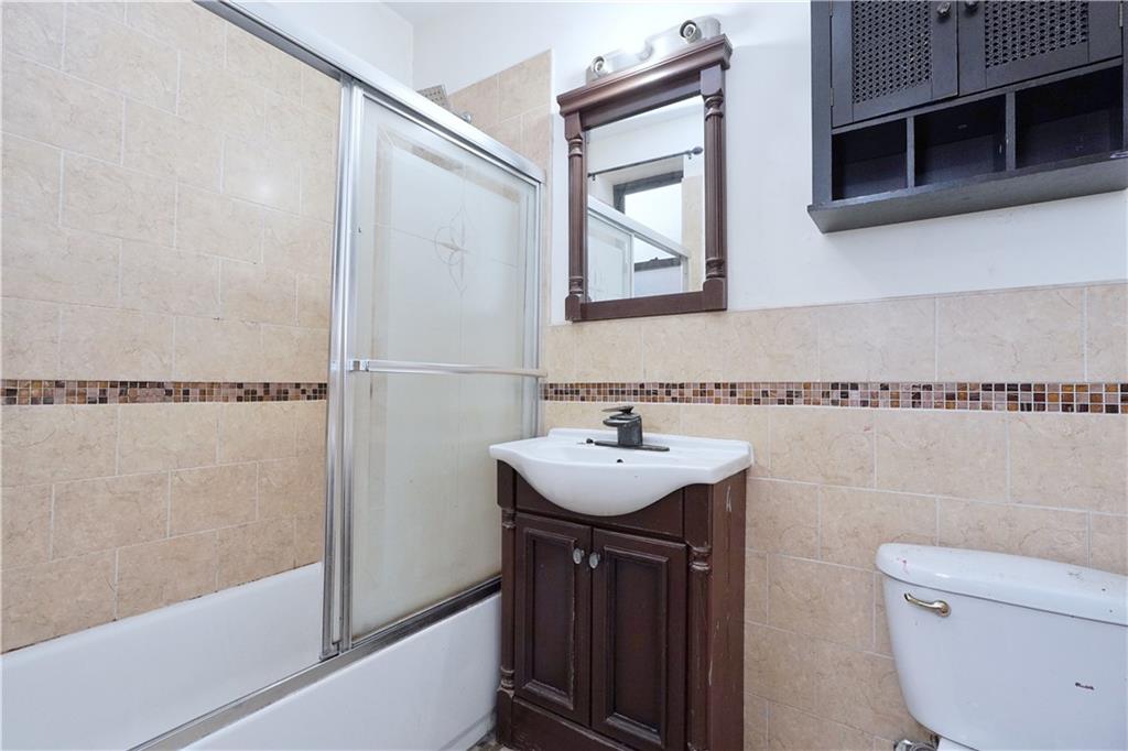 587 Van Siclen Avenue Brooklyn, NY 11207 - Photo 21 of 34 a bathroom with a sink a toilet a mirror and shower
