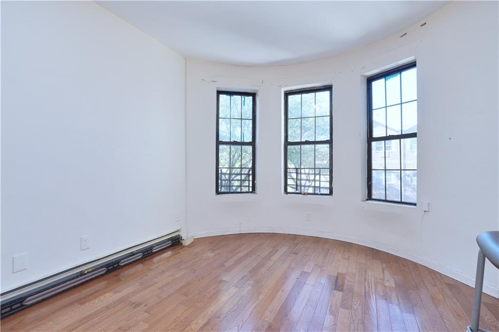 587 Van Siclen Avenue Brooklyn, NY 11207 - Photo 6 of 34 an empty room with wooden floor and windows