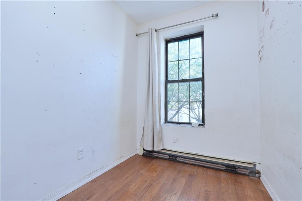 587 Van Siclen Avenue Brooklyn, NY 11207 - Photo 10 of 34 an empty room with wooden floor and windows