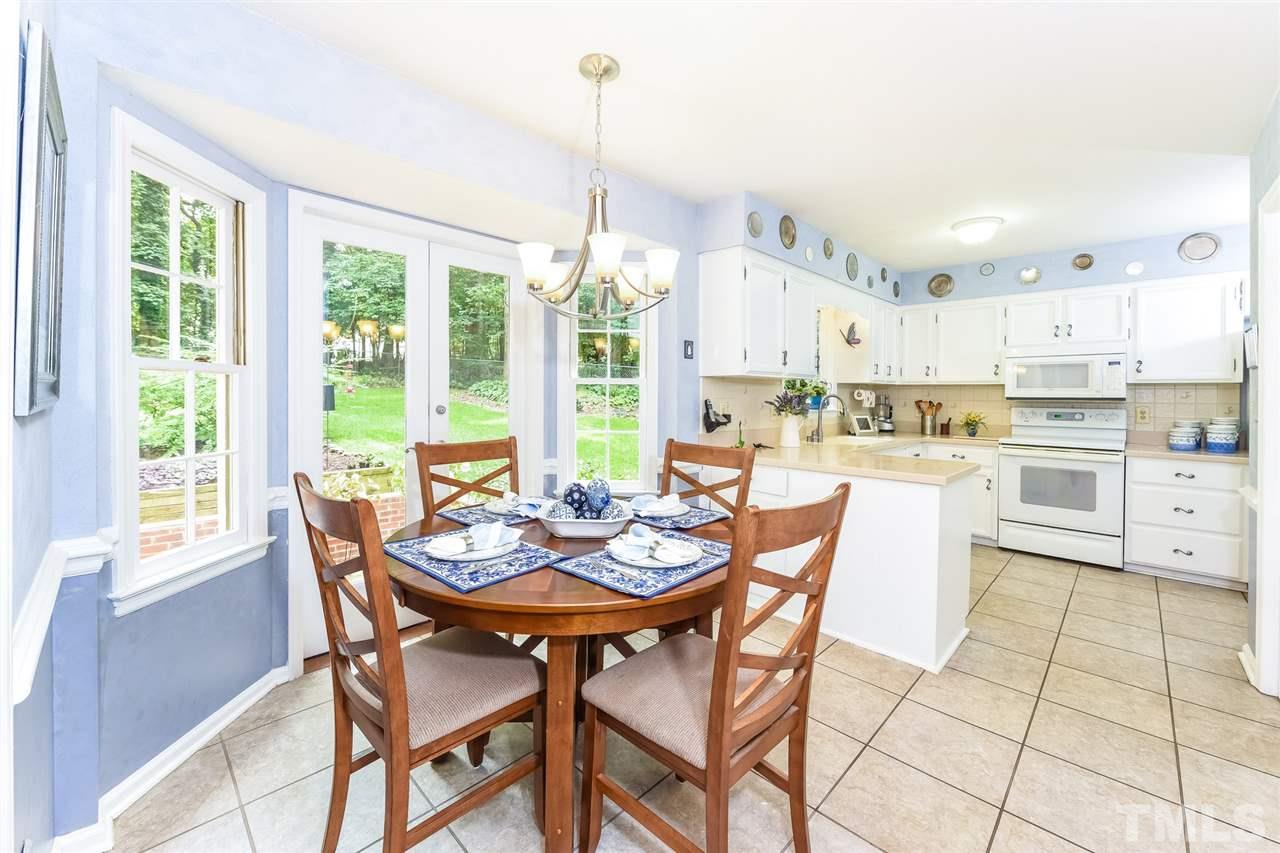 9716 Rock Creek Road Raleigh, NC 27613 - Photo 11 of 25 a dining room with stainless steel appliances a table and chairs with kitchen view